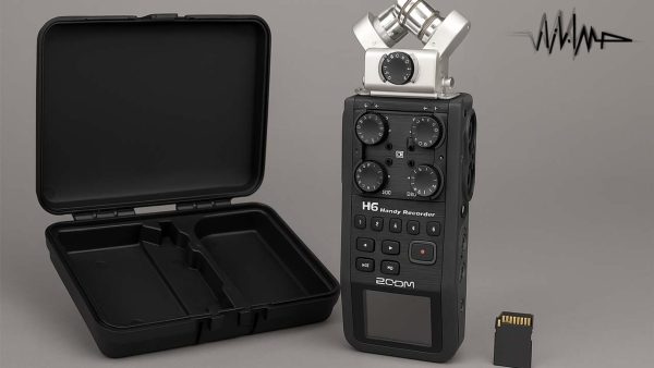 آکادمی صدابازار 13 نمای نزدیک از رکوردر Zoom H6 بههمراه کپسول میکروفن XY متصل، در کنار کیس محافظ باز و کارت حافظه SD که روی سطحی خاکستری قرار گرفتهاند
